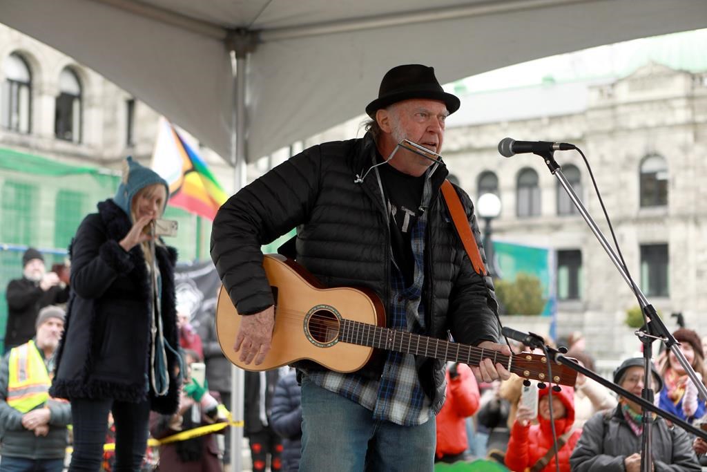 Rock legend Neil Young performs during a rally against the destruction of old growth forests on the front lawn of the legislature in Victoria, B.C., on Saturday, February 25, 2023. 