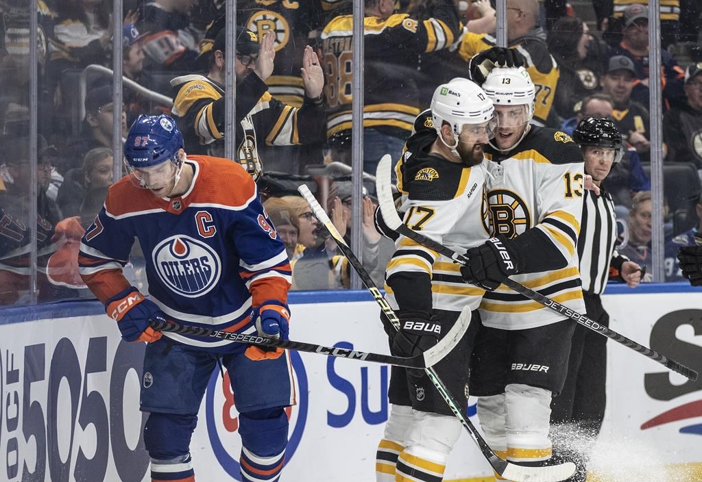 Boston Bruins’ Nick Foligno (17) and Charlie Coyle (13) celebrate a goal as Edmonton Oilers’ Connor McDavid (97) skates past during first period NHL action in Edmonton on Monday February 27, 2023.