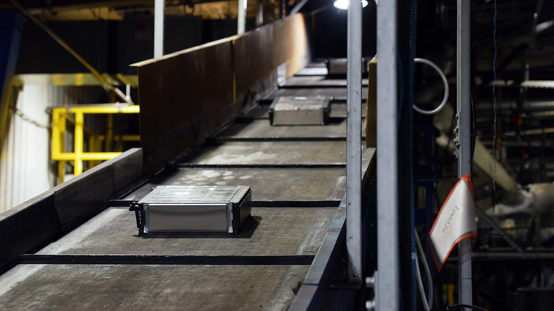 Old or defective electric car battery modules travel up the conveyor. Each will drop into a chemical solution before being shredded.