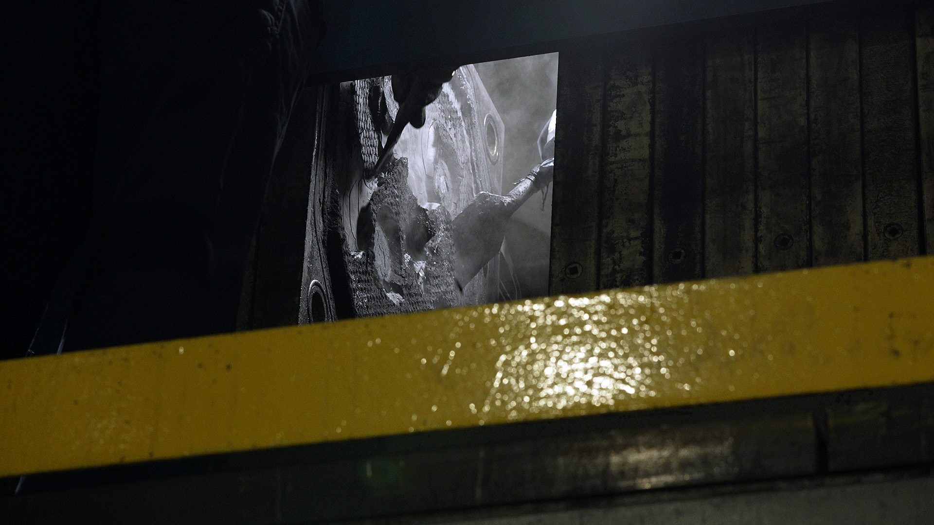 A worker scraps the black mass off plates into large white bags. It will be shipped off to a third party to be processed further.