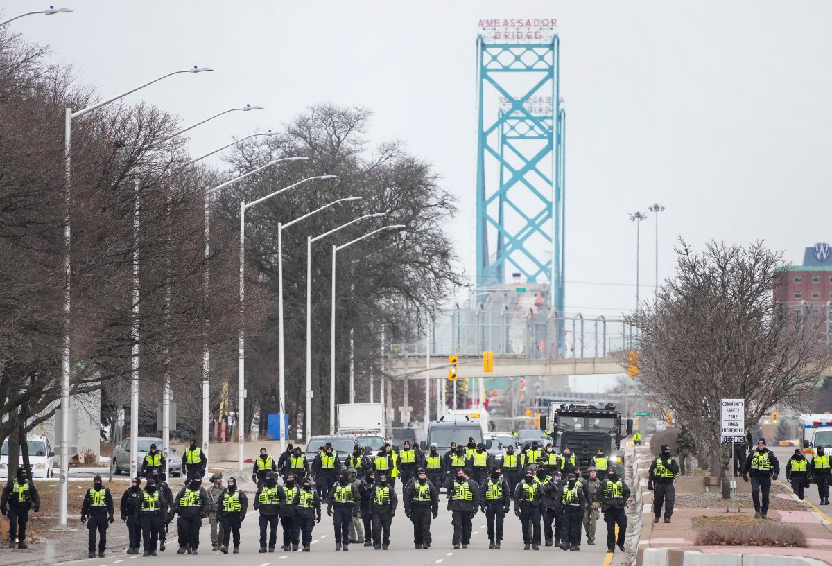Police walk the line to remove all truckers and supporters after a court injunction gave police the power to enforce the law after protesters blocked the access leading from the Ambassador Bridge, linking Detroit and Windsor, as truckers and their supporters continue to protest against COVID-19 vaccine mandates and restrictions, in Windsor, Ont., Sunday, Feb. 13, 2022. THE CANADIAN PRESS/Nathan Denette.
