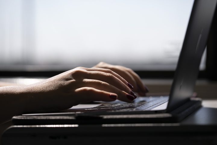 A person's hands sit on a laptop keyboard