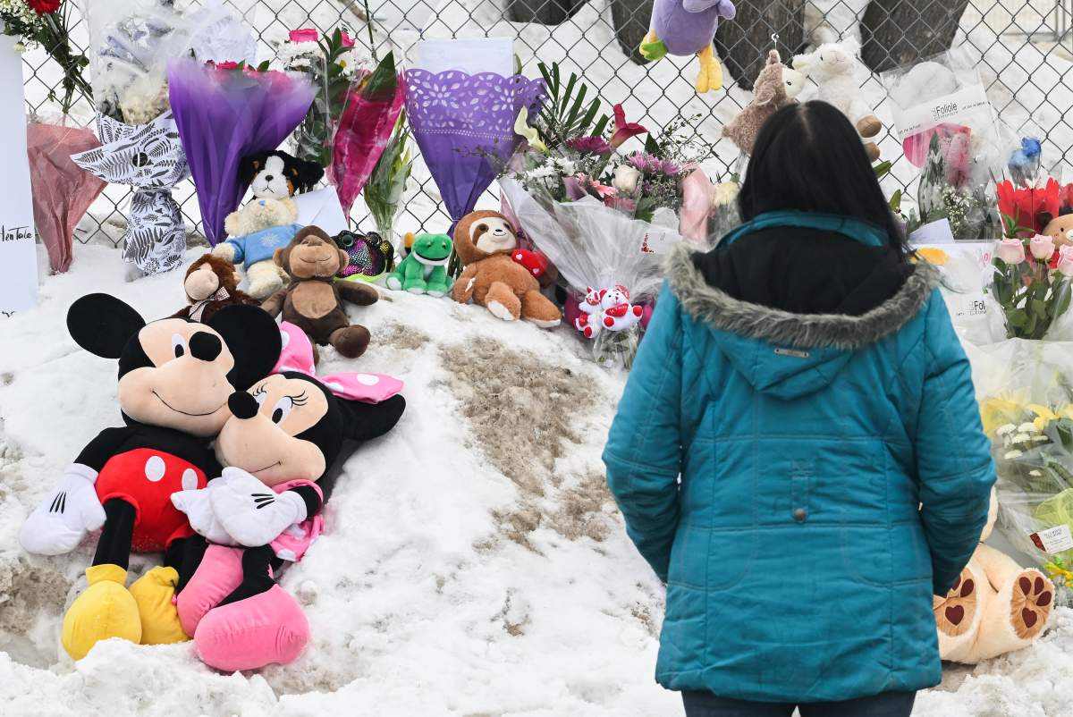 A woman stands next to a memorial at the site of a daycare centre in Laval, Que, Thursday, February 9, 2023, where a bus crashed into the building killing two children.