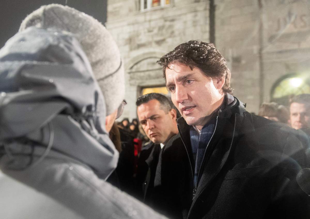 Prime Minister Justin Trudeau talks to a man as he attends a vigil at a church near the site of a daycare centre where two children lost their lives after a city bus crashed into the building in Laval, Que, Thursday, February 9, 2023. THE CANADIAN PRESS/Graham Hughes