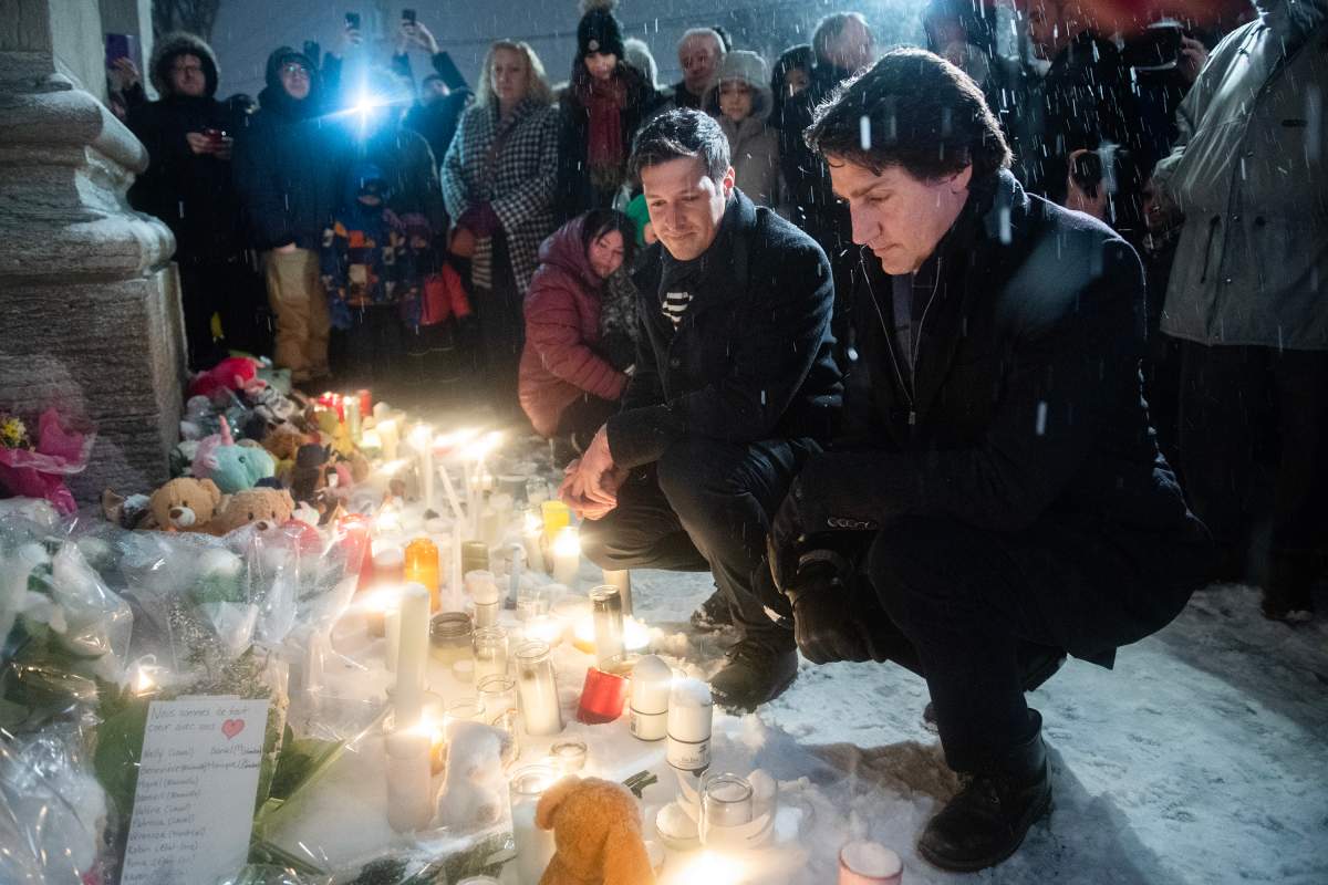 Prime Minister Justin Trudeau, right, and Laval Mayor Stephane Boyer attend a vigil at a church near the site of a daycare centre where two children lost their lives after a city bus crashed into the building in Laval, Que, Thursday, February 9, 2023. THE CANADIAN PRESS/Graham Hughes