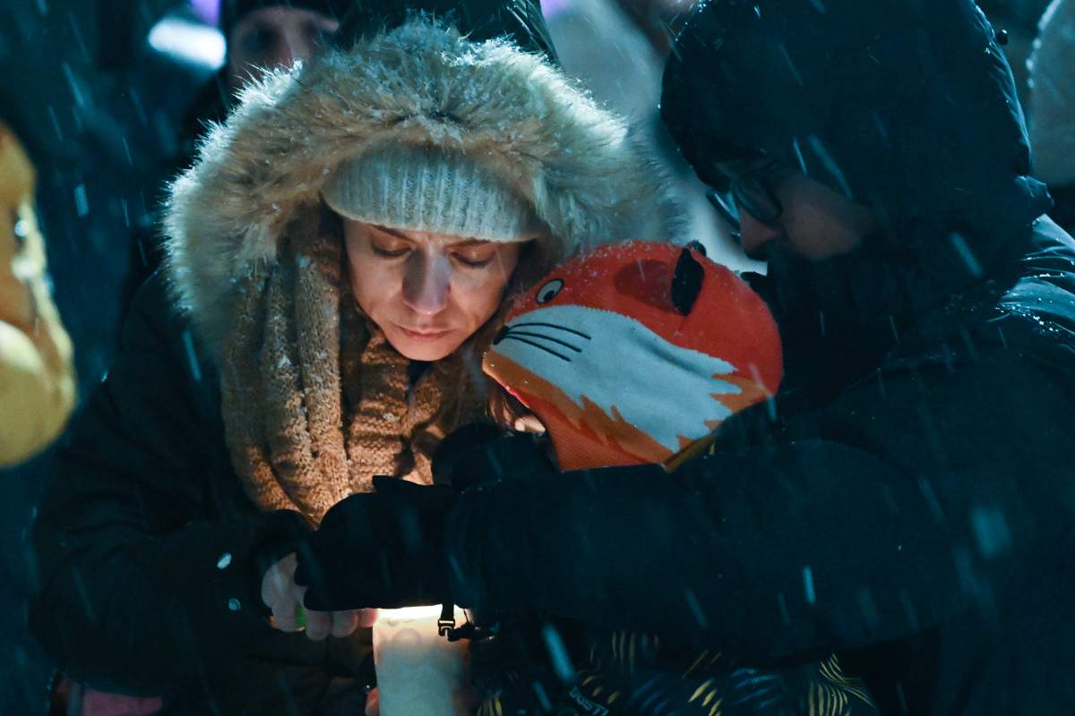 People light a candle during a vigil at a church near the site of a daycare centre where two children lost their lives after a city bus crashed into the building in Laval, Que, Thursday, February 9, 2023. THE CANADIAN PRESS/Graham Hughes