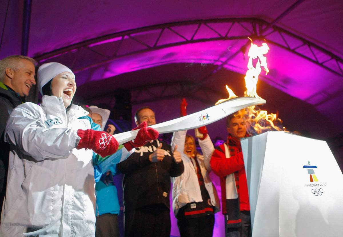 Torch bearer Robyn Ainsworth, left, who lit the Olympic cauldron at the 1988 Calgary Olympics, lights a Vancouver 2010 cauldron in Calgary, Alta., Monday, Jan. 18, 2010.