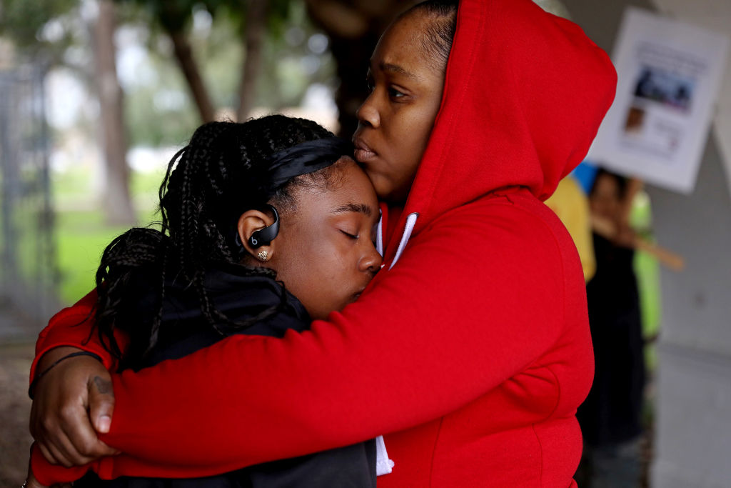 Arian Lowe, 15, left, daughter of Anthony Lowe, is consoled by Keyenie Jackson, aunt and sister of Lowe, and family members demand answers about Huntington Park police shooting of double amputee Anthony Lowe at a press conference in front of the Huntington Park Police Department on Monday, Jan. 30, 2023 in Huntington Park, Calif.