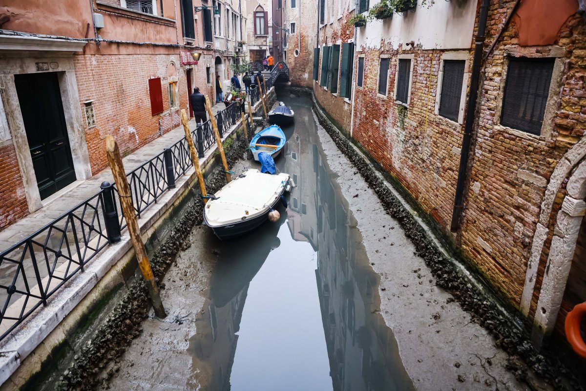 A mostly dried canal in Venice, Italy. There are boats on the ground.