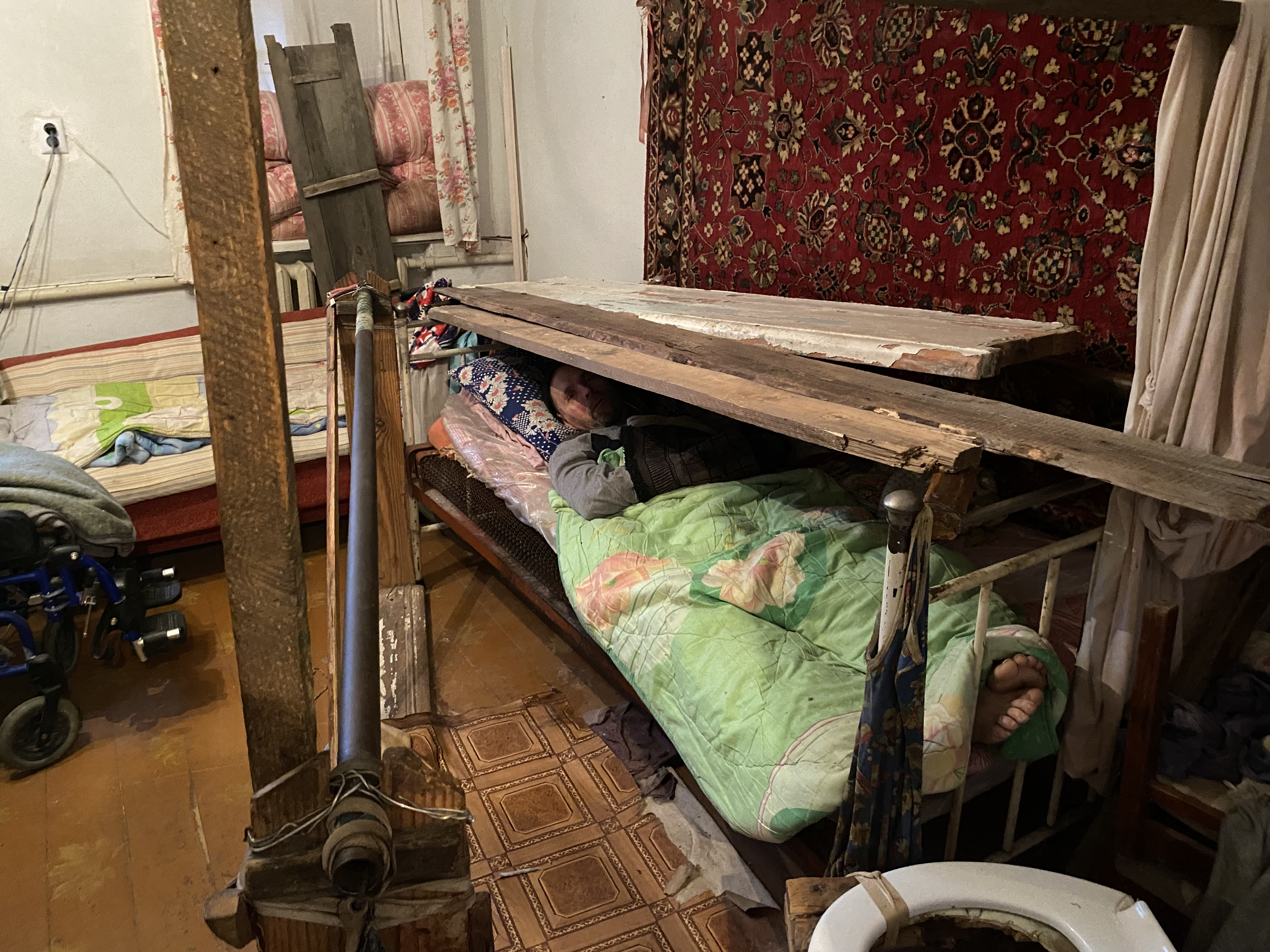 Bedridden man in bed protected by wooden planks, Marhanets, Ukraine, Jan. 23, 2023.