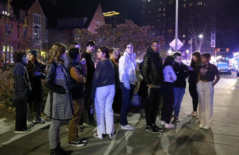 Students gather outside. It is dark.