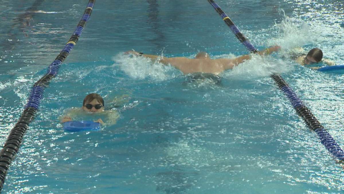People swimming in a swim lane at a recreation centre pool.