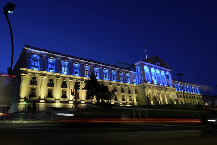 Vehicles drive past the Portuguese Parliament lit with the Ukrainian flag colours to mark the one-year anniversary of the invasion of Ukraine, in Lisbon, as night falls Thursday, Feb. 23, 2023.