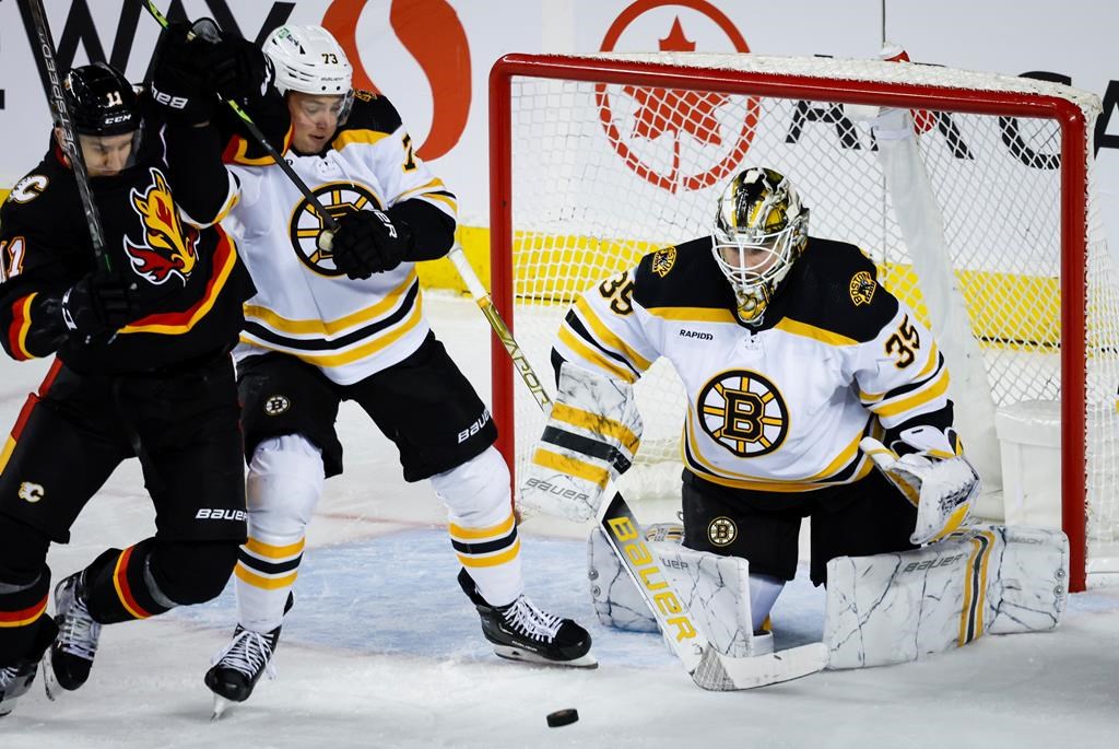 Boston Bruins defenceman Charlie McAvoy, centre, keeps Calgary Flames forward Mikael Backlund, left, away from the puck as goalie Linus Ullmark looks on during second period NHL hockey action in Calgary, Tuesday, Feb. 28, 2023.