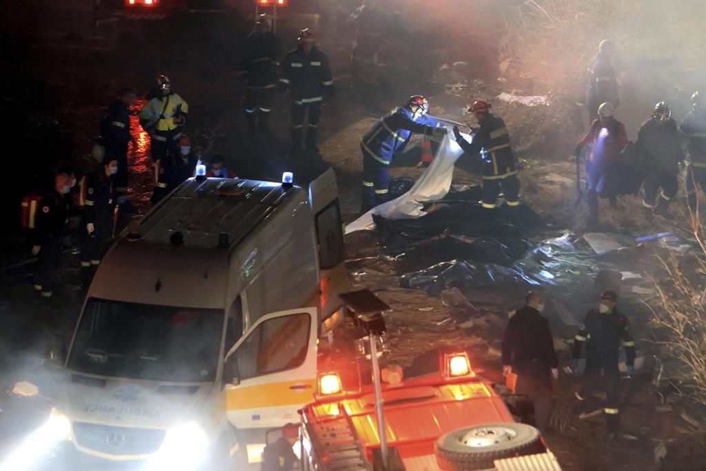 Firefighters collect bodies after a collision in Tempe near Larissa city, Greece early Wednesday, March 1, 2023.