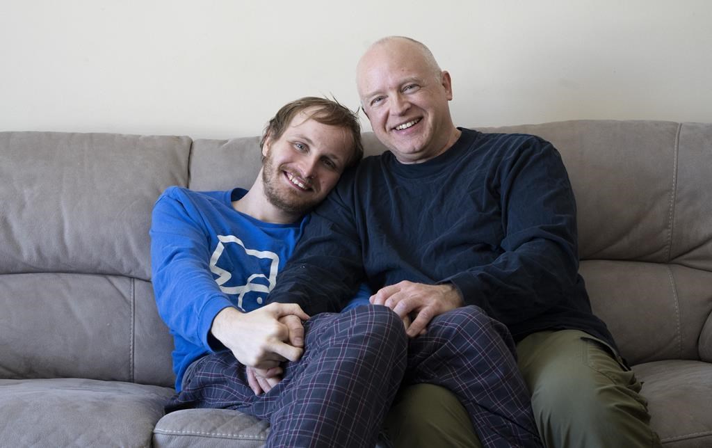 Andrew Kavchak and his son Steven pose for a photo on the sofa in their home in Ottawa, Friday, March 3, 2023. Kavchak, 60, a former federal public servant, retired to provide care for his son Steven, 22, who lives with autism spectrum disorder. Kavchak was told the wait-list for his son Steven to enter a group home would be 10 years long.