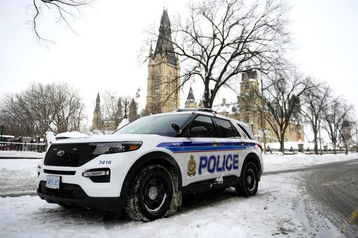 An Ottawa Police officer sits in their cruiser on Wellington Street below Parliament Hill in Ottawa, on Friday, Jan. 27, 2023. What was supposed to be a friendly Friday night charity hockey game between the Ottawa Police Service and the Ottawa Fire Service has ended in controversy over the jerseys worn by the force.
