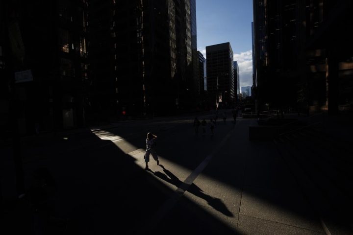 Pedestrians walk through a sliver of sunlight in the financial district in downtown Toronto on Wednesday July 6, 2022. ISS Corporate Solutions, Inc. says for the first time ever women hold one third of the board director positions across companies listed on the S&P/TSX composite. 