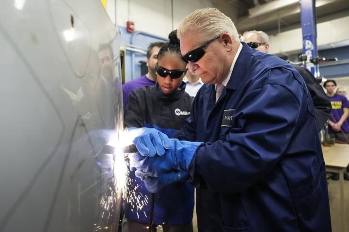 Ontario Premier Doug Ford, right, gets help from grade 11 student Shannon Williams, 16, as they practise plasma welding on a car hood while visiting St. Mary Catholic Secondary School in Pickering, Ont., on Wednesday, March 8, 2023. 