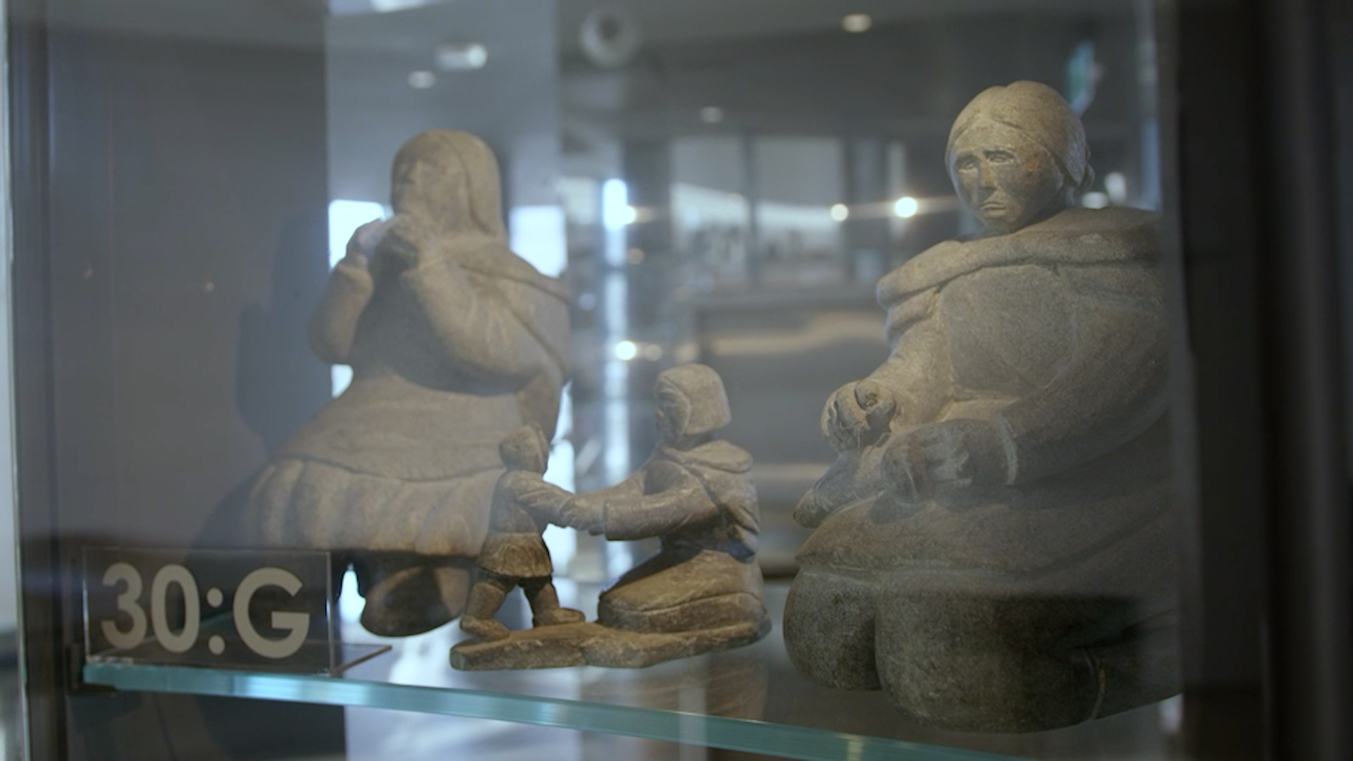 Stone carvings inside a glass and mirrored display case, part of the visible vault at Quamajuq-Winnipeg Art Gallery.