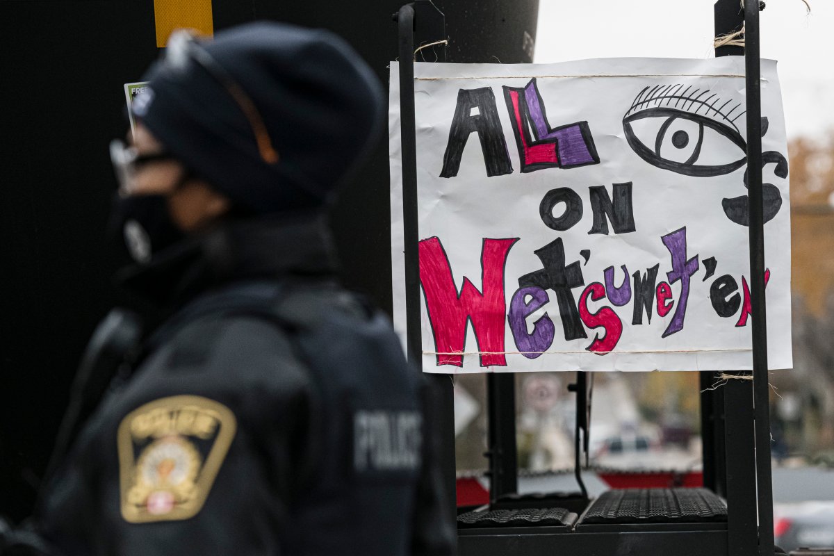 A police officer is pictured in front of a sign that reads 'all eyes on wet'suwet'en'