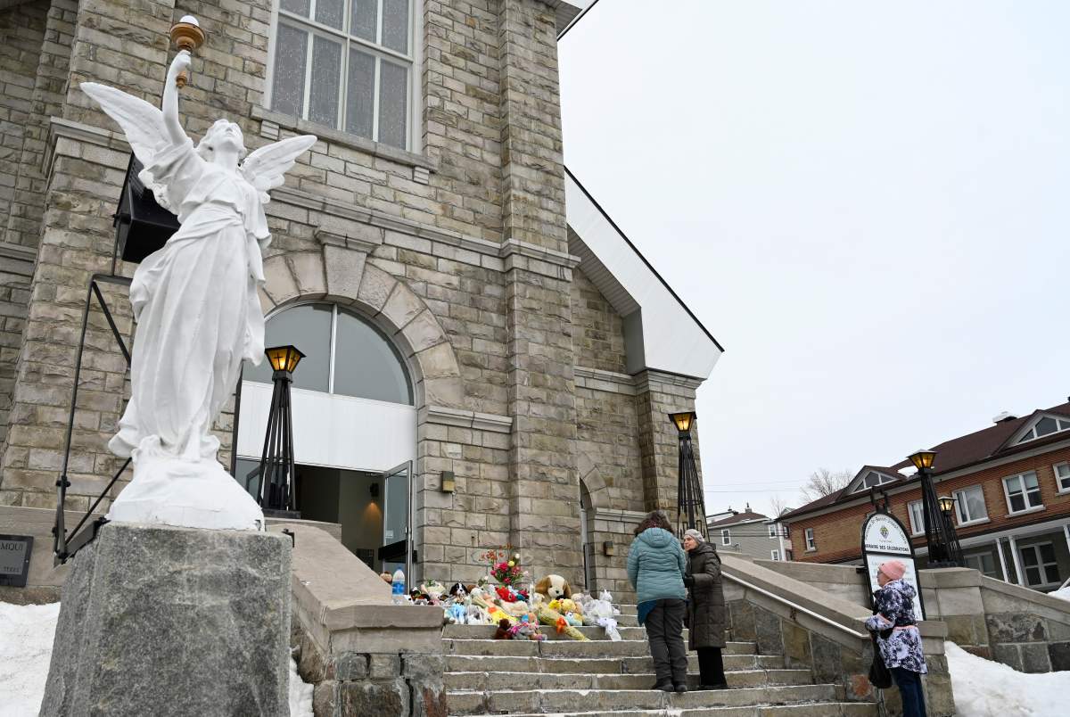 People gather on the steps of the church, praying for the victims, Tuesday, March 14, 2023 in Amqui, Que.