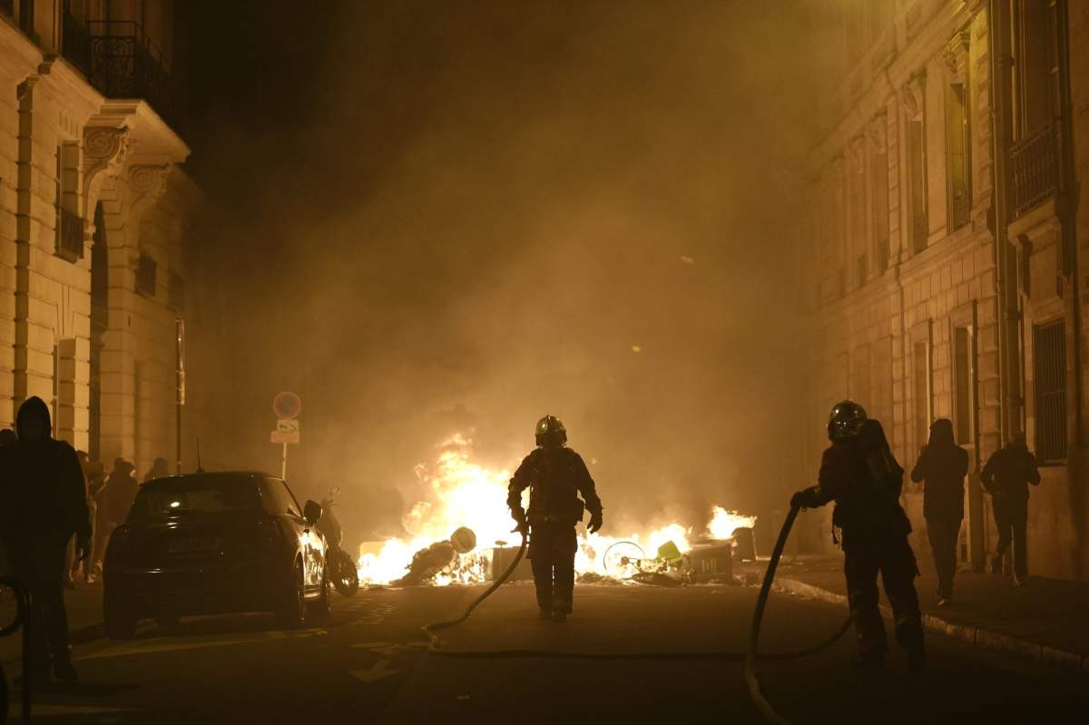Firefighters put out a fire near Concorde square after a demonstration in Paris, Thursday, March 16, 2023.