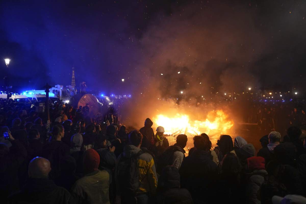 Demonstrators gather next to a burning barricade as they stage a protest in Paris, Friday, March 17, 2023
