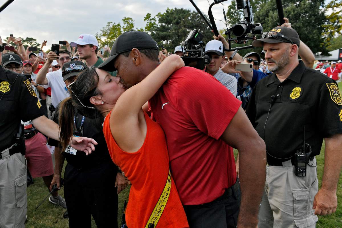 Tiger Woods and Erica Herman kiss on a golf course.