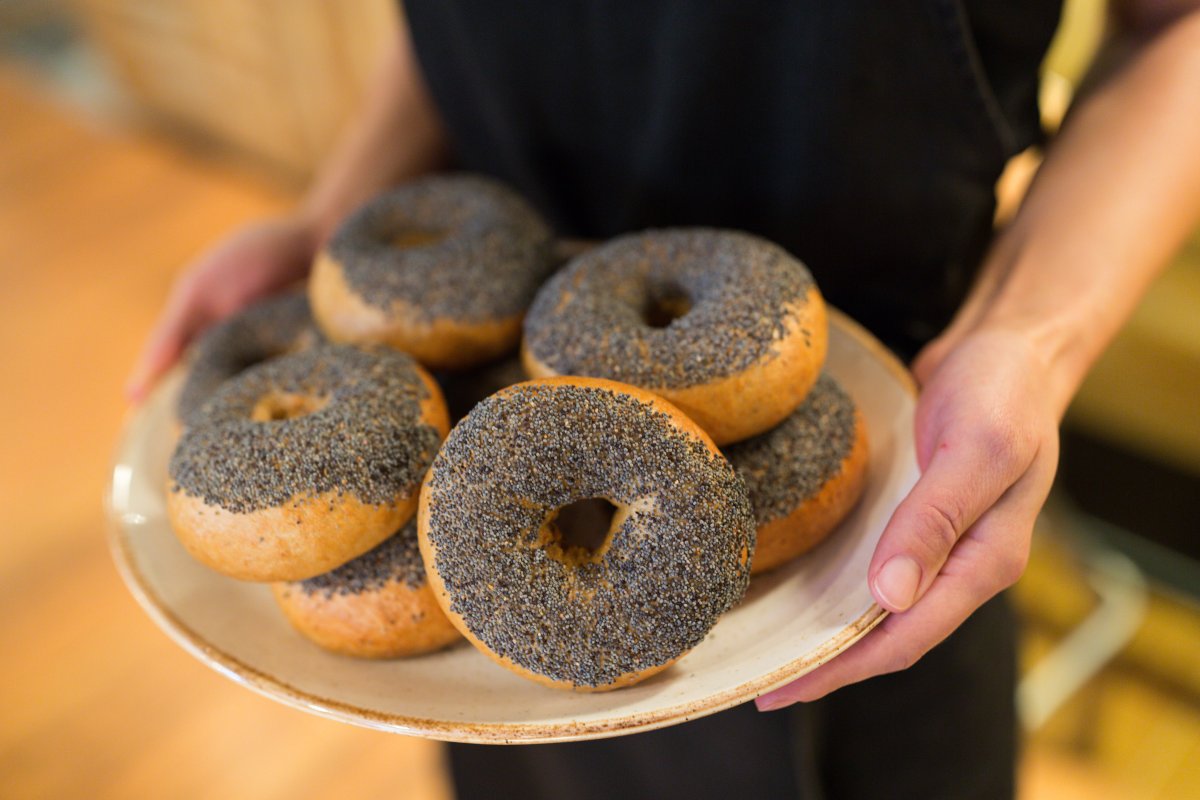 A person holding a plate of poppyseed bagels.