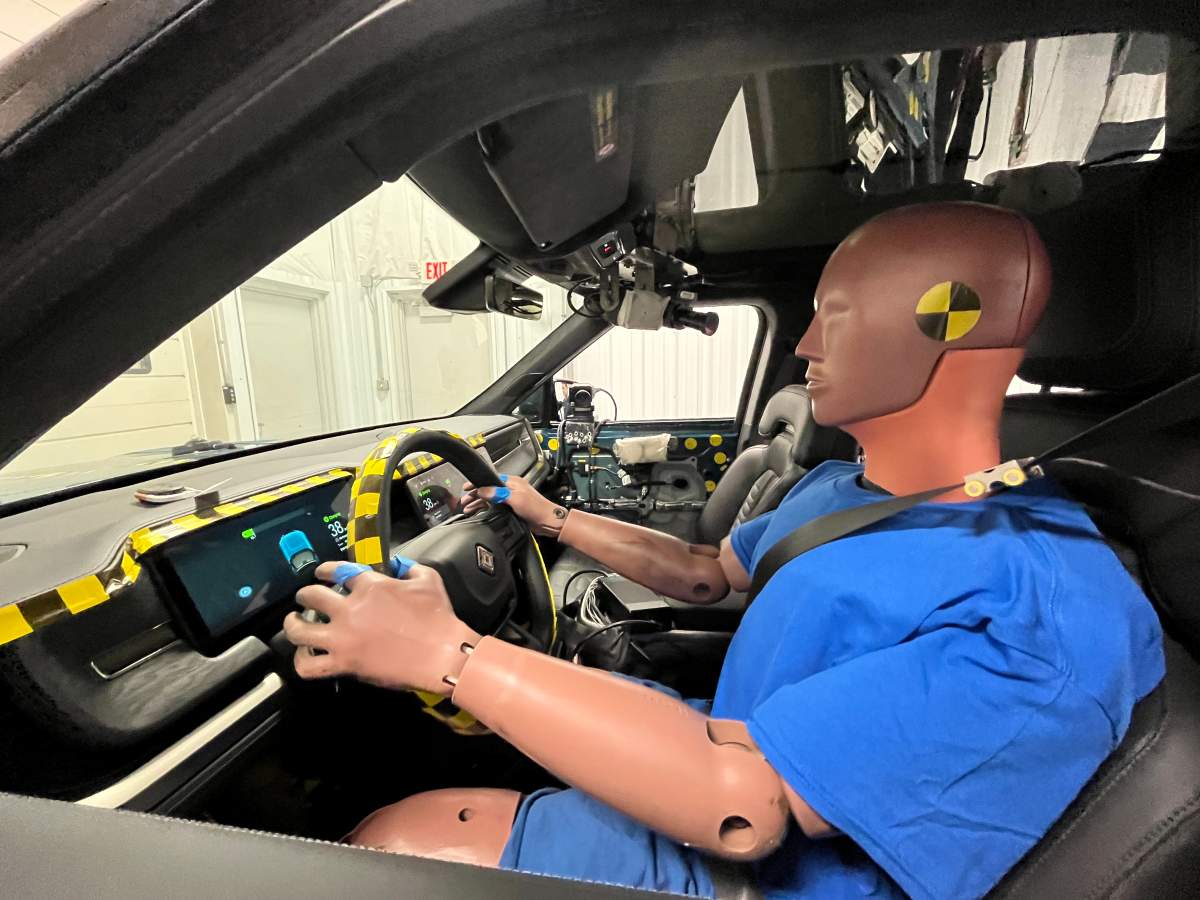 A crash test dummy is positioned inside an electric vehicle ahead of a crash test