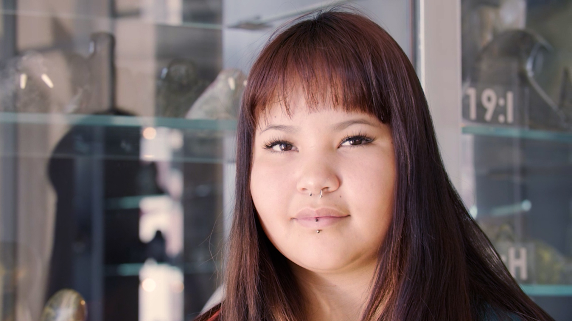 Marisa is a young woman with long, dark auburn hair and face framing bangs. She's looking into the camera. She had dark brown eyes.