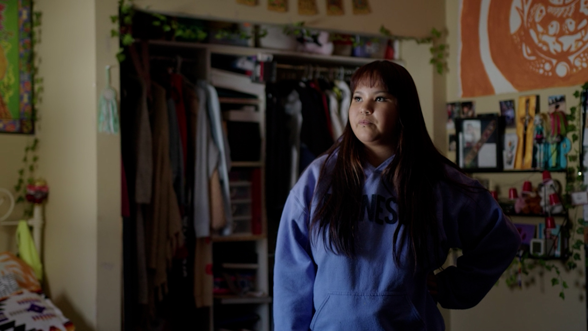 Marisa St. Godard stands in her bedroom at home, southeast of Winnipeg. She's wearing a purple hooded sweater and has long, dark auburn hair with bangs.