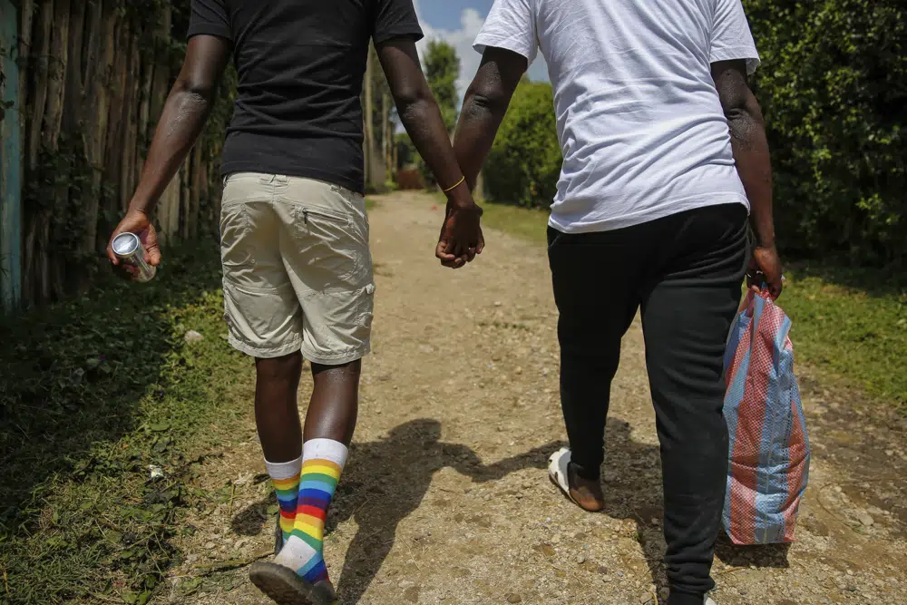 Two men hold hands on a dirt road.