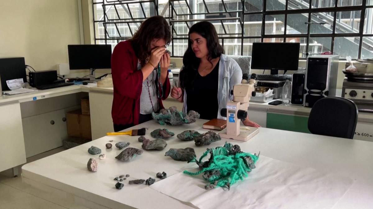 Researcher Fernanda Avelar Santos looks through a microscope at "plastic rocks" found on Trindade Island in the state of Espirito Santo, at the laboratory of the Federal University of Parana.