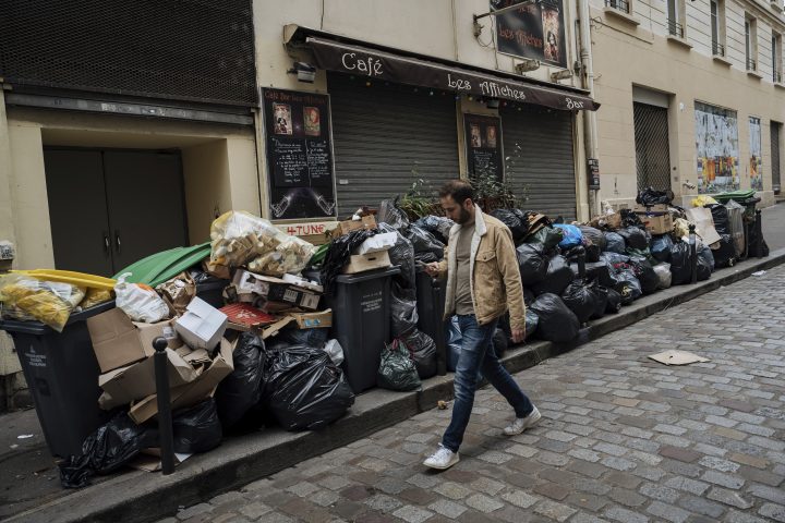 A man walks past uncollected garbage in Paris, Monday, March 13, 2023. (AP Photo/Lewis Joly)