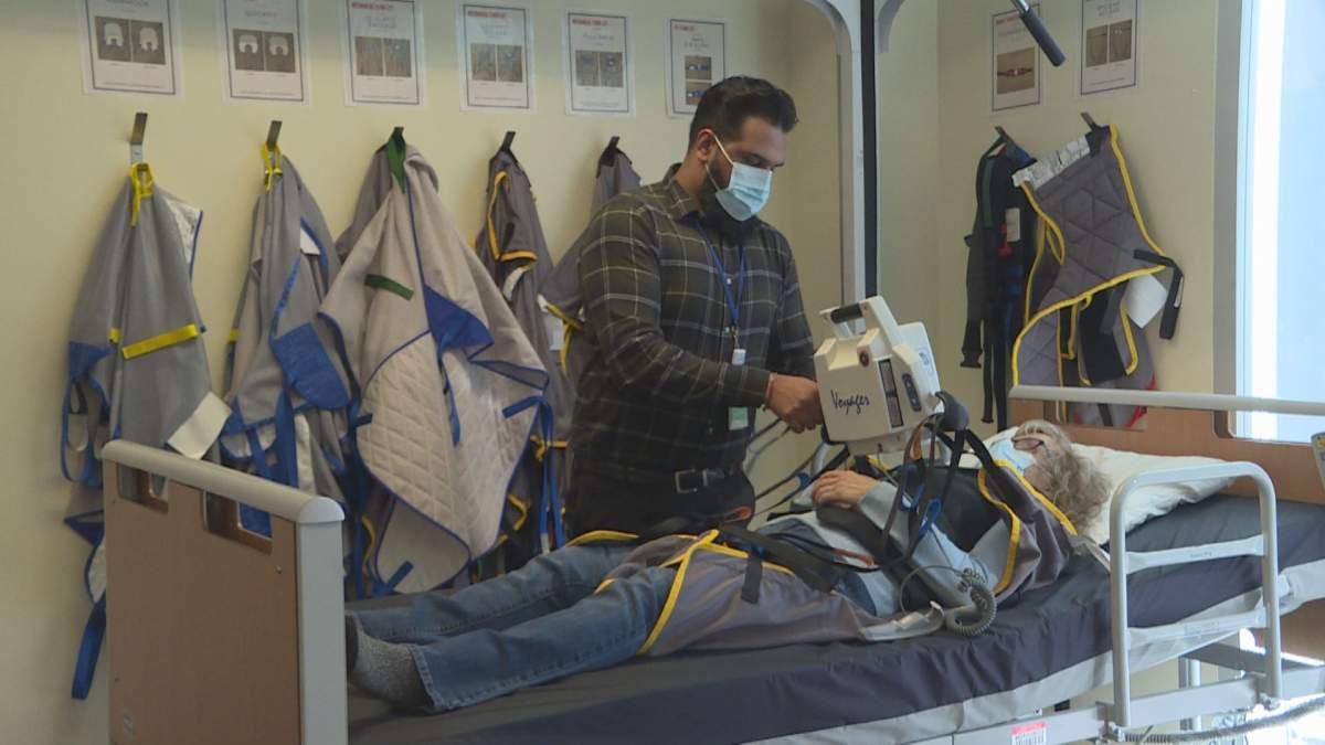 Instructor Hardeep Deol operates an overhead lift for Elizabeth Vokey's safe transfer from bed to wheelchair -- one of the tasks students like Vokey will learn to do for others in their month-long paid training to become uncertified home care attendants with the WRHA.