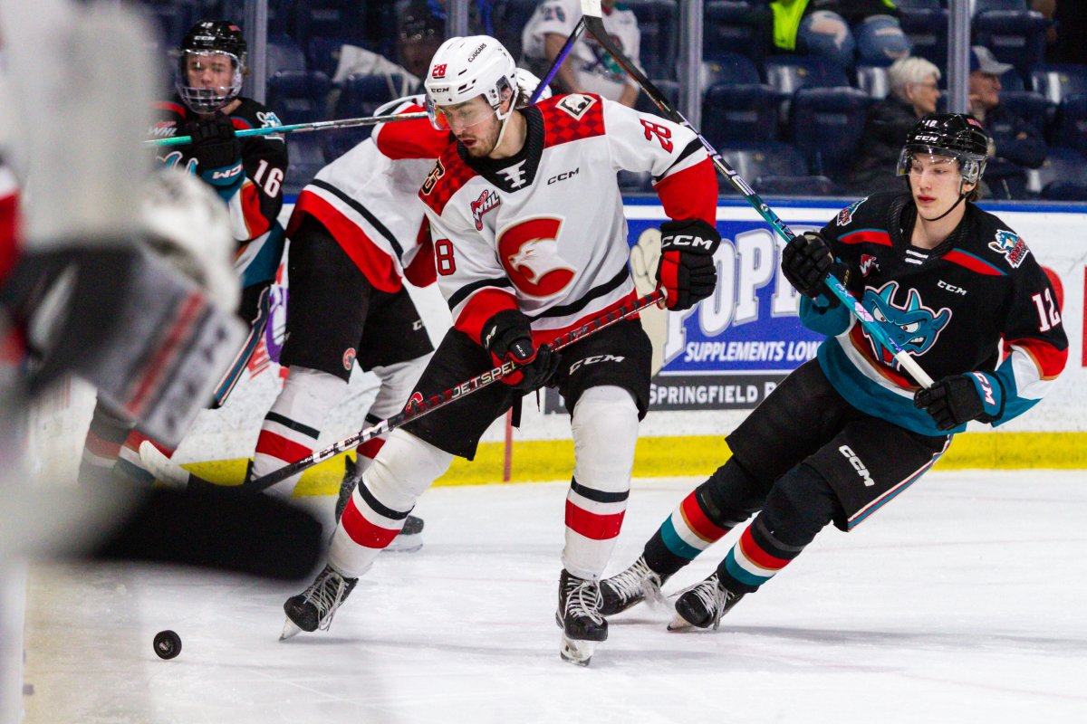 Blake Eastman of the Prince George Cougars, left, and Will Munro of the Kelowna Rockets look at the puck during WHL action in Kelowna, B.C., on Wednesday, March 8, 2023. Prince George won 6-2.