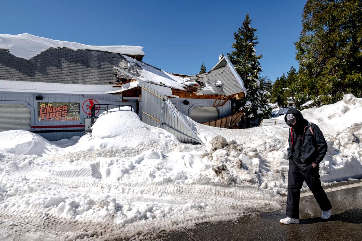 A man walks past a shop with its roof caved in from snow in southern California.