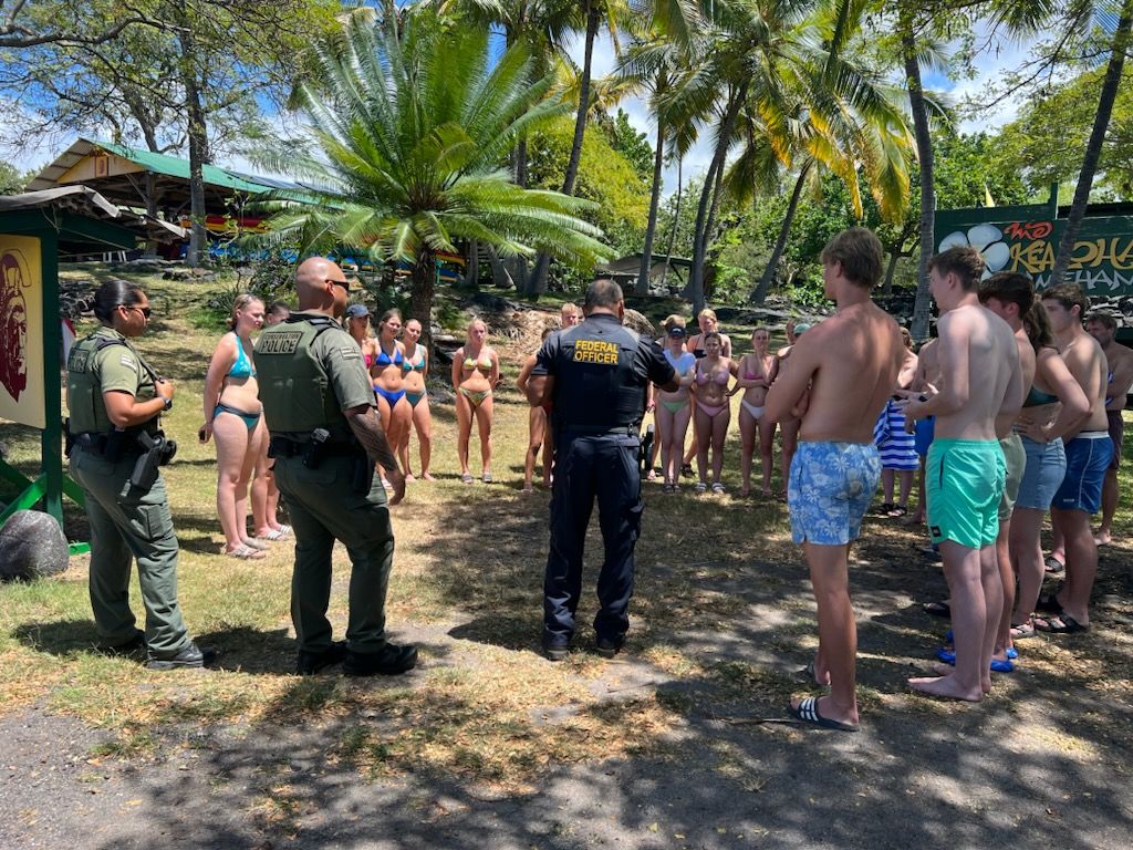 People in bathing suits stand beside uniformed officers.