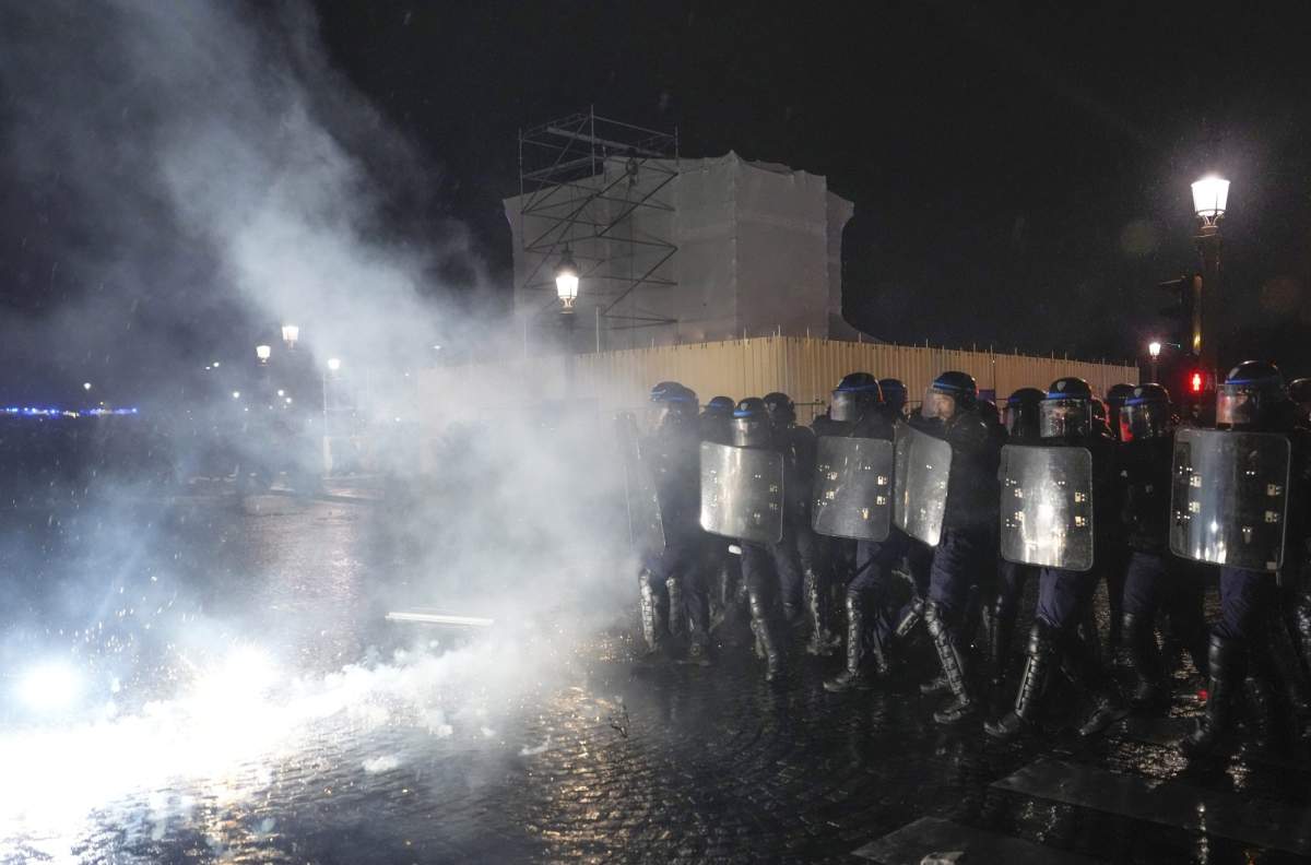 Police officers stand in the tear gas during a protest in Paris,