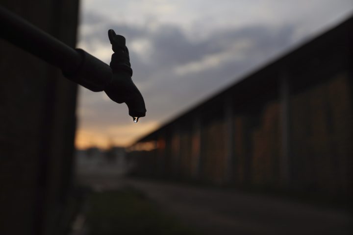 An outdoor water tap is shown with a sunset in the background