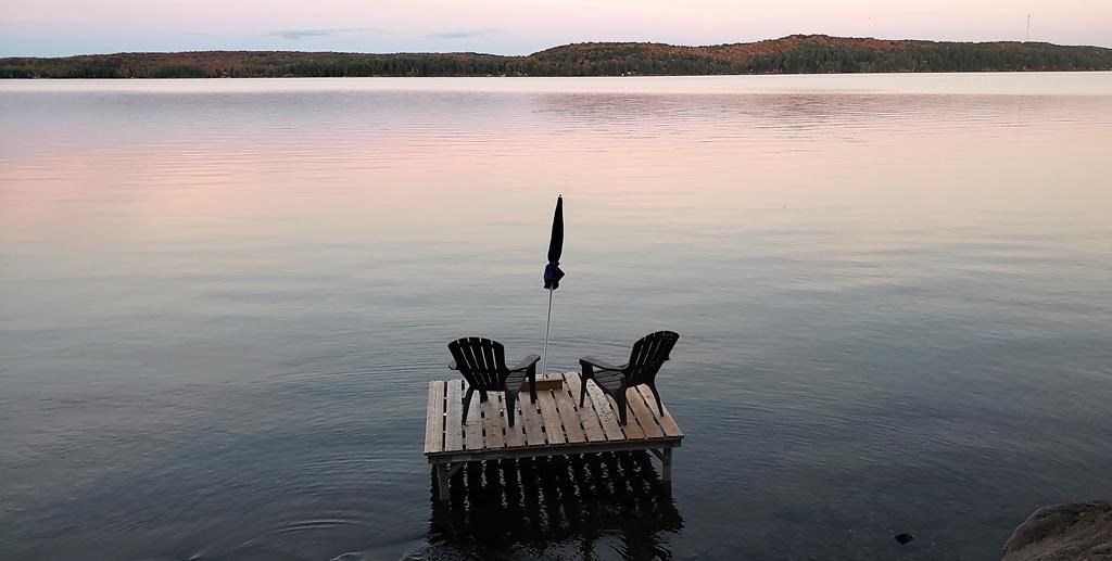Muskoka chairs sit on a dock looking over Boshkung Lake, in Algonquin Highlands, Ont., Monday, Oct. 5, 2020.