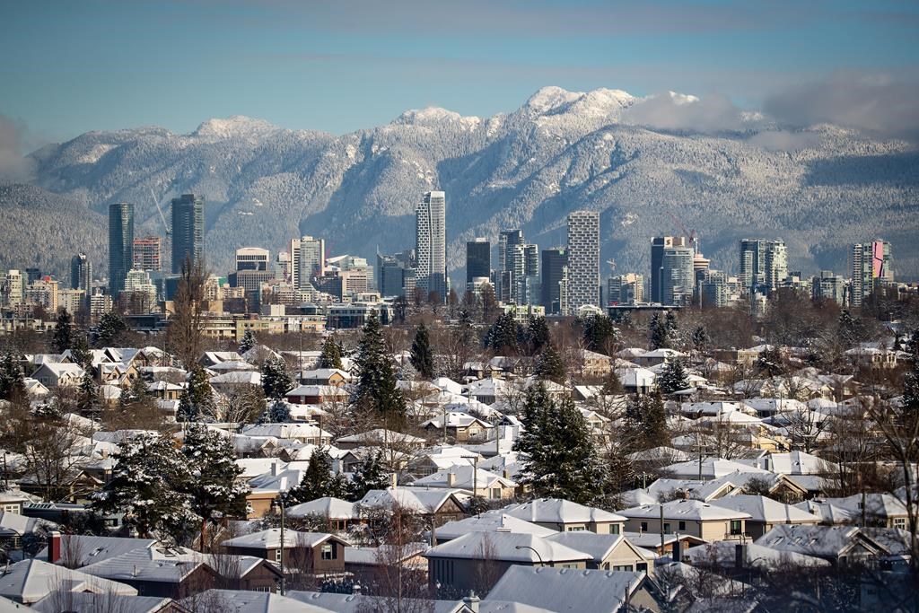 Snow-covered houses and the downtown skyline are seen with the north shore mountains in the distance, in Vancouver, on Thursday, December 30, 2021.