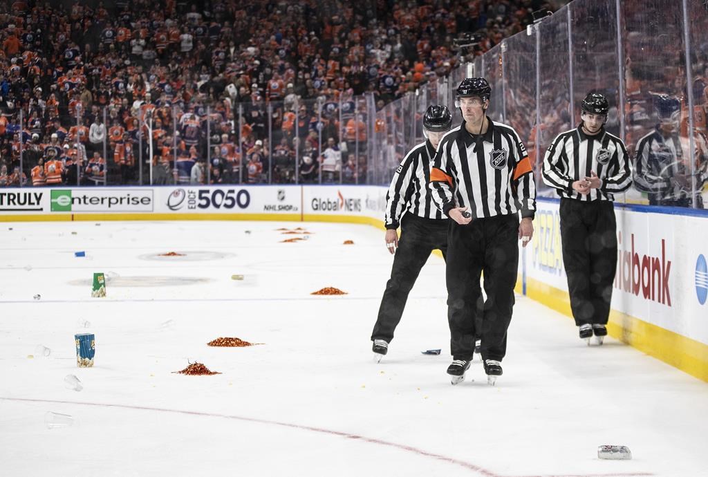 Refees skate past garbage thrown on the ice after Los Angeles Kings win over the Edmonton Oilers during overtime NHL Stanley Cup first round playoff action in Edmonton on Monday April 17, 2023.