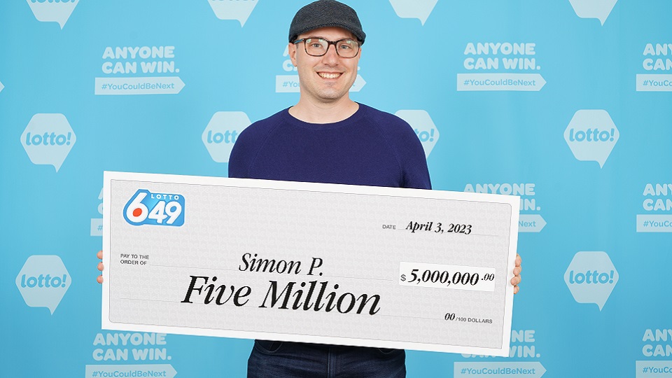 Simon Pleau of North Vancouver holds a cheque worth $5 million after winning the Lotto 6-49 Classic Jackpot draw on March 29.