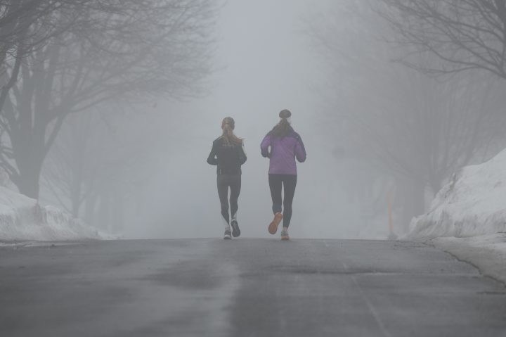 People jog through the Central Experimental Farm during heavy fog and rain in Ottawa, on Saturday, Dec. 31, 2022.