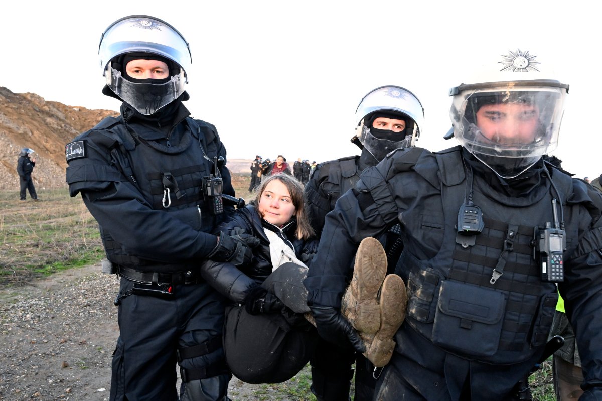 Three German police officers dressed in black and wearing balaclavas and white helments carry Swedish climate activist Greta Thunberg away from the edge of the Garzweiler opencast lignite coal mine during a protest action by climate activists after the clearance of Lützerath, Germany, Tuesday, Jan. 17, 2023.