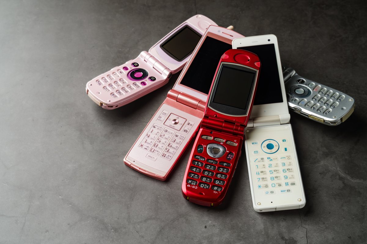 File - A stack of old flip phones on a dark background.