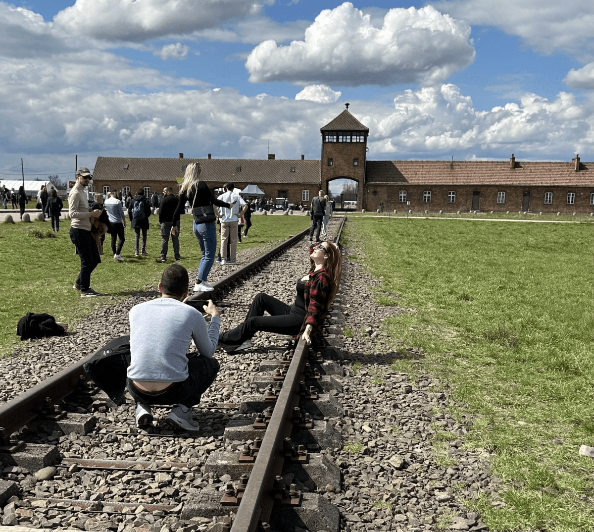 A woman poses for a photo on the train tracks in from of Auschwitz.
